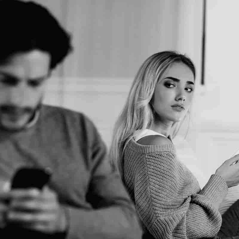 Hombre chateando por WhatsApp con su pareja al lado, representando investigaciones de infidelidades en Málaga